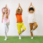 Three diverse children practicing yoga indoors, showcasing joy and balance.
